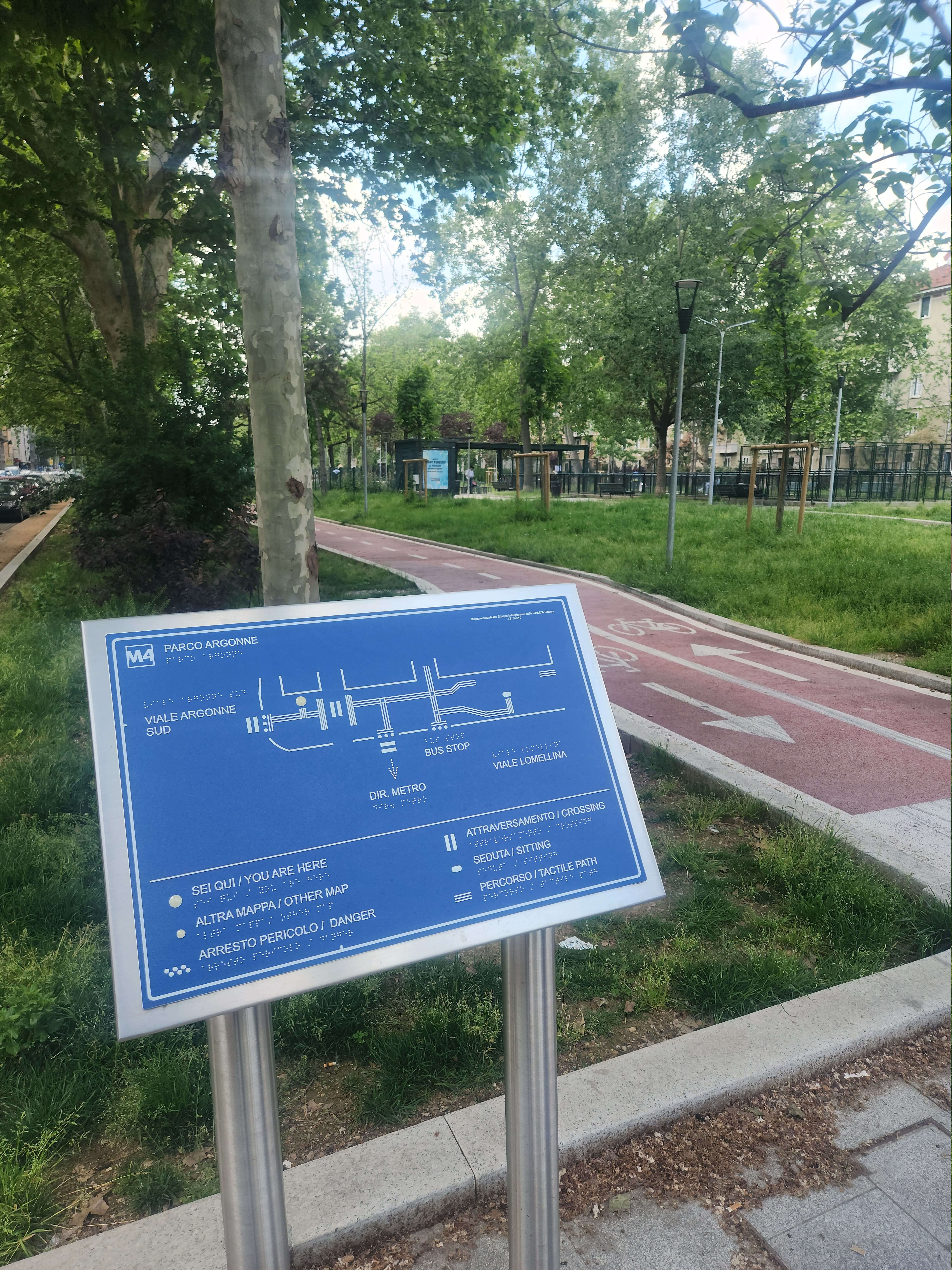 Mappa tattile blu situata nel Parco Argonne di Milano, indicante direzioni, fermate bus e percorsi ciclabili accessibili.